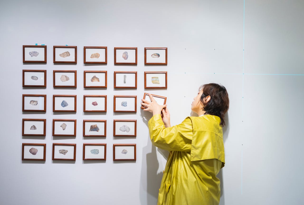 A curator arranging framed art in a modern exhibition in Tokyo, Japan.
