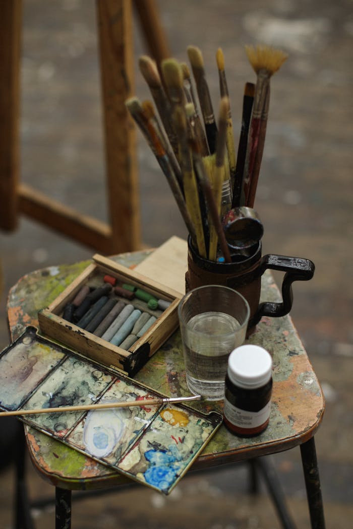 Close-up of art supplies on a wooden stool, perfect for creative inspiration.